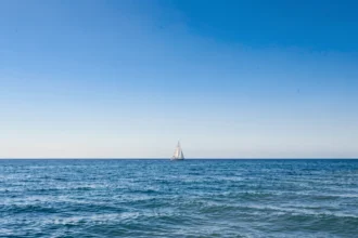 Ciel bleu dégagé au-dessus d'une mer calme avec un voilier