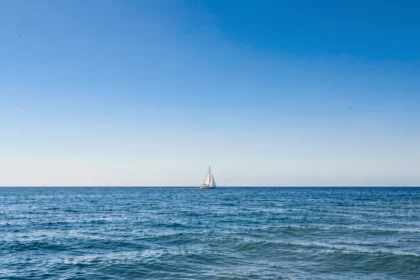 Ciel bleu dégagé au-dessus d'une mer calme avec un voilier